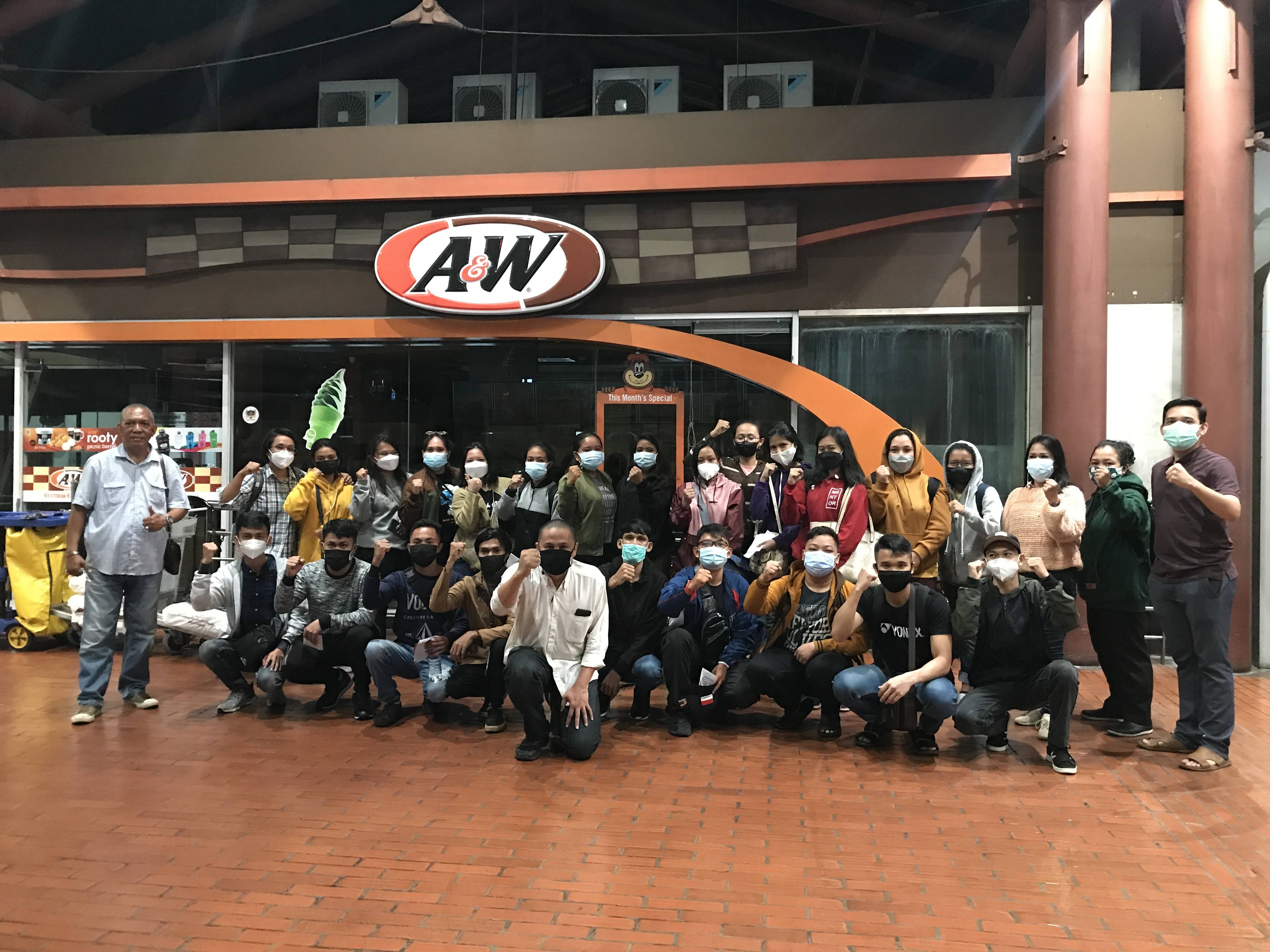 sekumpulan orang sedang berfoto bersama menggunakan masker dengan latar belakang restoran A&W
